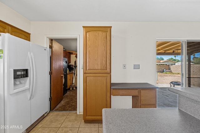 kitchen featuring light tile patterned floors, dark countertops, and white refrigerator with ice dispenser