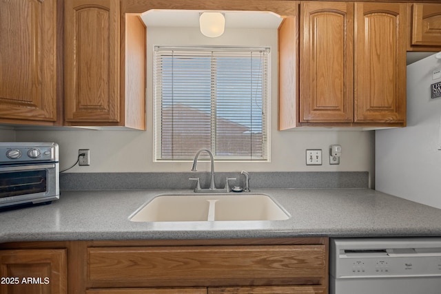 kitchen featuring a toaster, light countertops, brown cabinets, dishwasher, and a sink