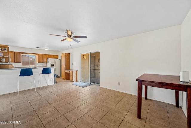 unfurnished living room featuring light tile patterned floors, a ceiling fan, and baseboards