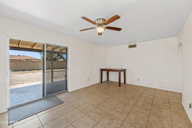 spare room featuring light tile patterned floors, a ceiling fan, visible vents, and arched walkways