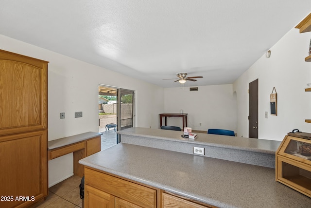 kitchen with light tile patterned floors, ceiling fan, brown cabinets, and visible vents