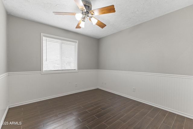 2633 E Garnet Ave, Mesa, AZ 85204 - spare room featuring a wainscoted wall, a ceiling fan, dark wood-style floors, a textured ceiling, and baseboards