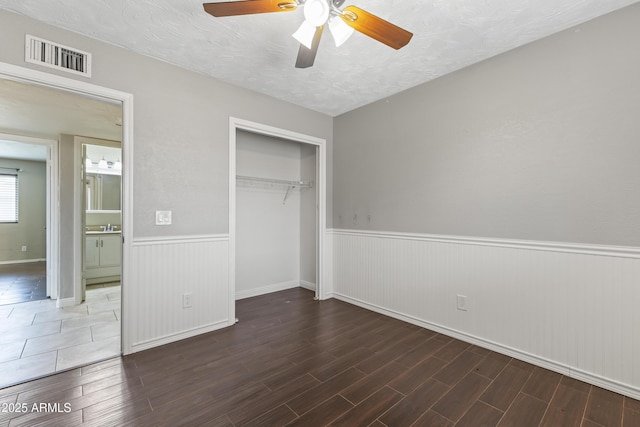 2633 E Garnet Ave, Mesa, AZ 85204 - unfurnished bedroom featuring a wainscoted wall, wood finished floors, a closet, a textured ceiling, and ceiling fan
