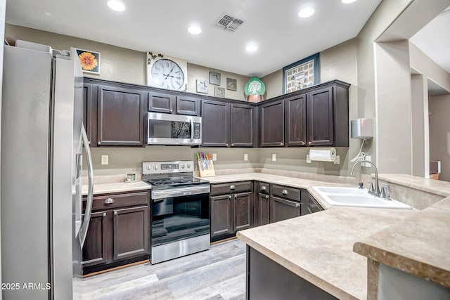 3948 W Rushmore Dr, Anthem, AZ 85086 - kitchen featuring dark brown cabinets, a sink, light wood-type flooring, stainless steel appliances, and visible vents