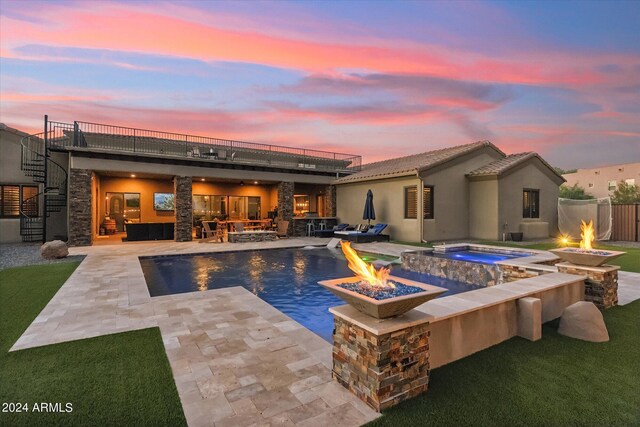 pool at dusk with an in ground hot tub, an outdoor living space with a fire pit, and a patio area