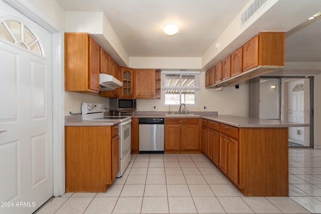 kitchen with kitchen peninsula, appliances with stainless steel finishes, light tile patterned floors, and sink