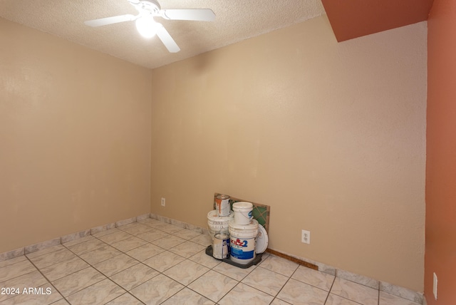 tiled empty room featuring ceiling fan and a textured ceiling