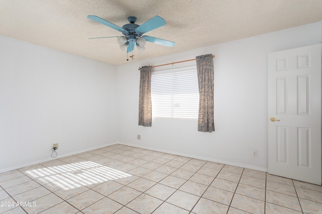 tiled empty room with ceiling fan and a textured ceiling