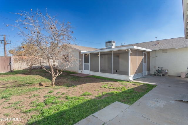 rear view of house with a lawn, a sunroom, central air condition unit, and a patio