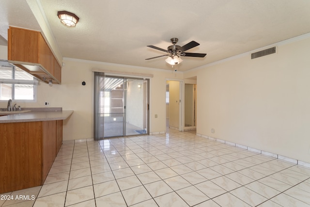 kitchen with sink, ceiling fan, ornamental molding, a textured ceiling, and light tile patterned floors