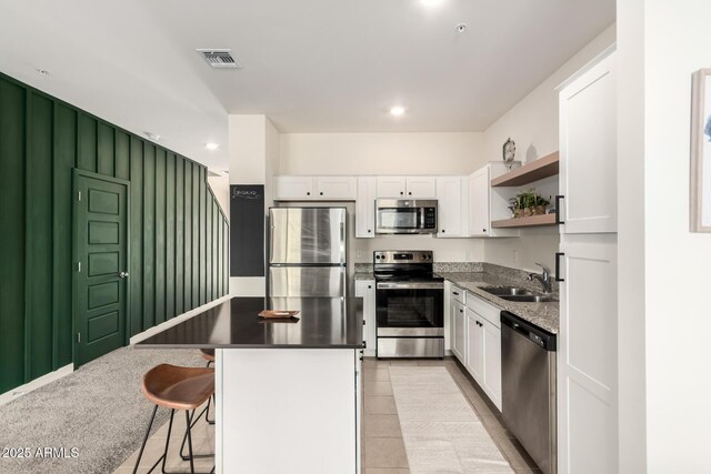 2256 W Laurie Ln, Phoenix, AZ 85021 - kitchen with stainless steel appliances, a sink, open shelves, white cabinetry, and a kitchen island
