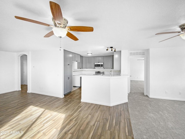 kitchen featuring gray cabinets, hardwood / wood-style floors, a kitchen island with sink, ceiling fan, and stainless steel appliances