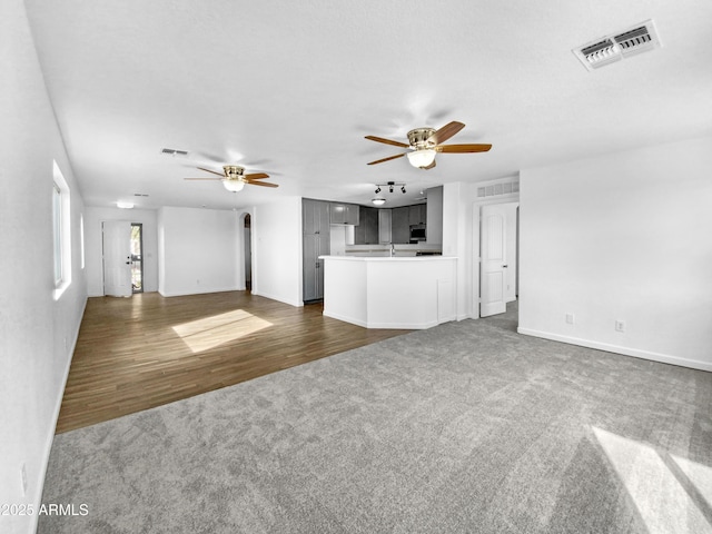 unfurnished living room featuring dark carpet and ceiling fan