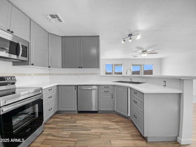 kitchen with gray cabinets, sink, hardwood / wood-style flooring, ceiling fan, and stainless steel appliances