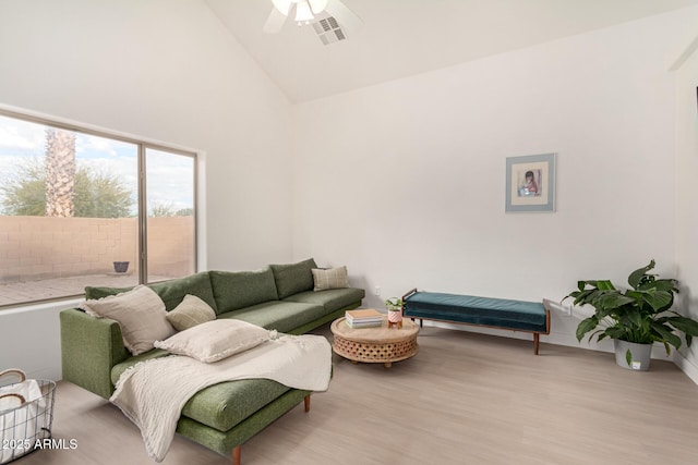 living room featuring light wood-style floors, visible vents, ceiling fan, and high vaulted ceiling