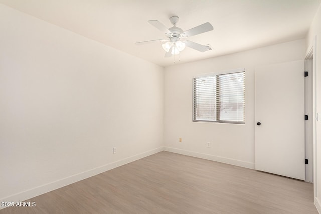 empty room featuring ceiling fan, light wood-style flooring, and baseboards