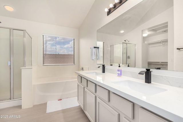 bathroom with a stall shower, a walk in closet, a garden tub, and a sink