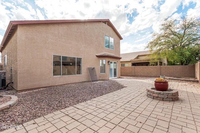 back of property featuring a fenced backyard, a patio, a fire pit, and stucco siding