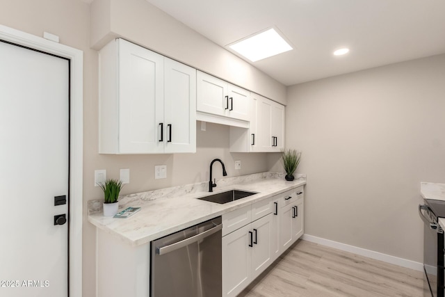kitchen featuring light wood finished floors, a sink, baseboards, white cabinetry, and dishwasher