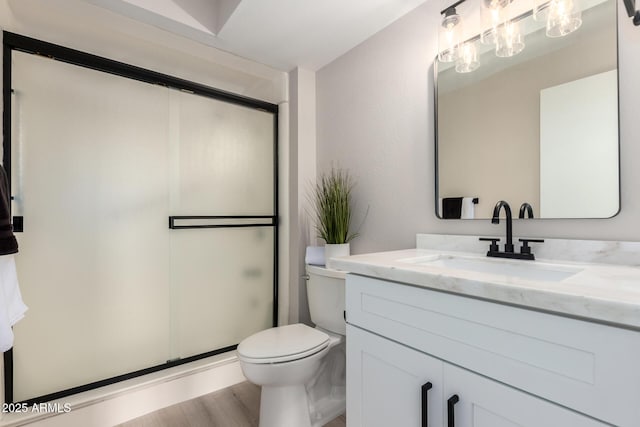 full bath with toilet, wood finished floors, vanity, and a stall shower