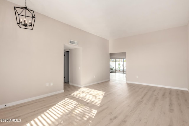 unfurnished room with baseboards, an inviting chandelier, visible vents, and light wood-style flooring