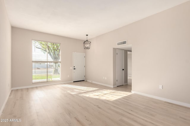 unfurnished room featuring light wood finished floors, baseboards, visible vents, and an inviting chandelier