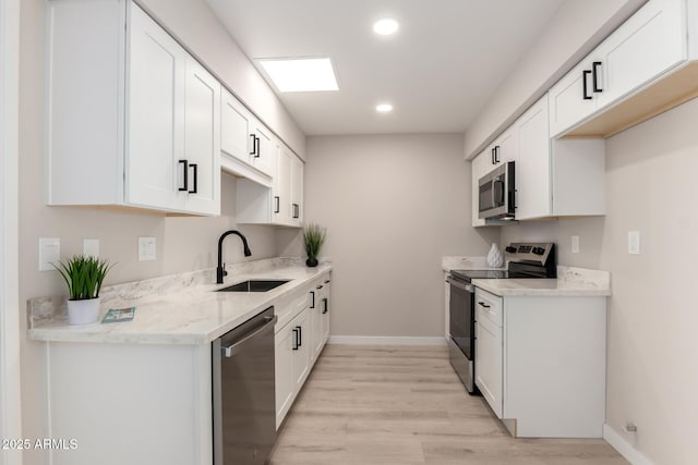 kitchen featuring a sink, light wood-type flooring, baseboards, white cabinetry, and appliances with stainless steel finishes