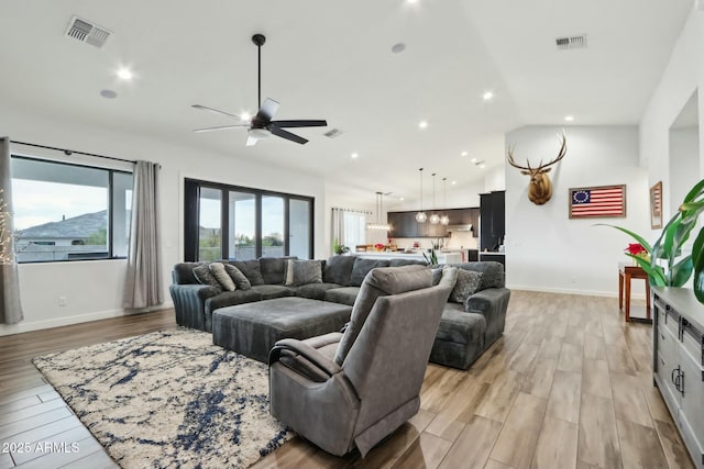 living room with high vaulted ceiling, ceiling fan, and light wood-type flooring