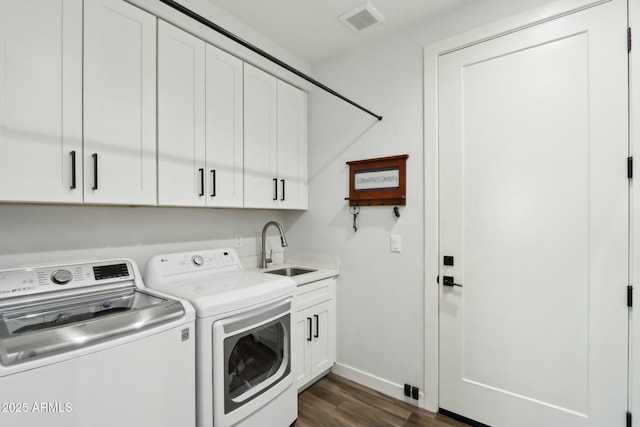 laundry area featuring cabinets, washing machine and clothes dryer, dark hardwood / wood-style floors, and sink