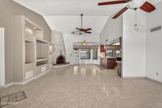 9839 W Utopia Rd, Peoria, AZ 85382 - unfurnished living room with ceiling fan, built in features, light tile patterned flooring, a textured ceiling, and a stone fireplace
