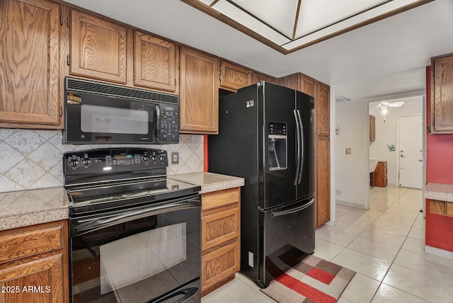 9839 W Utopia Rd, Peoria, AZ 85382 - kitchen with black appliances, brown cabinetry, tasteful backsplash, light tile patterned floors, and tile countertops