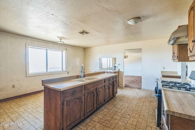 kitchen with a textured ceiling, sink, gas range oven, and range hood