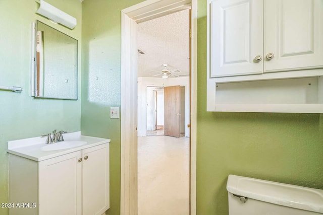 bathroom featuring a wall mounted air conditioner, vanity, ceiling fan, toilet, and a textured ceiling