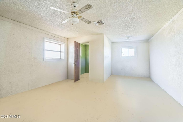 spare room with ceiling fan, a healthy amount of sunlight, and a textured ceiling