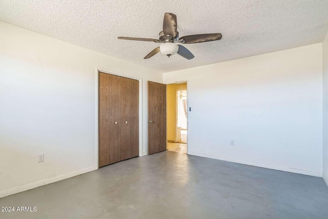 unfurnished bedroom with ceiling fan, concrete floors, a textured ceiling, and a closet