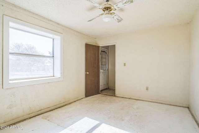 empty room with ceiling fan and a textured ceiling