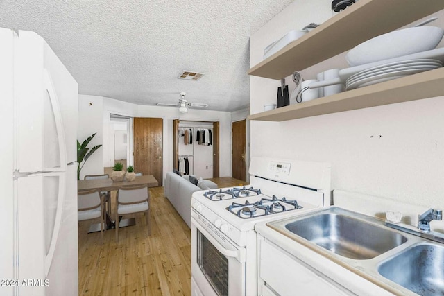 kitchen featuring light wood-type flooring, a textured ceiling, white appliances, ceiling fan, and white cabinetry