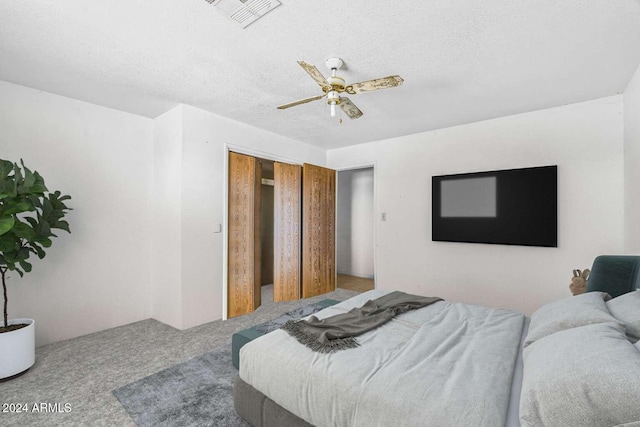 carpeted bedroom featuring ceiling fan and a textured ceiling