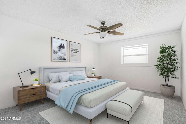 bedroom with ceiling fan, carpet floors, and a textured ceiling