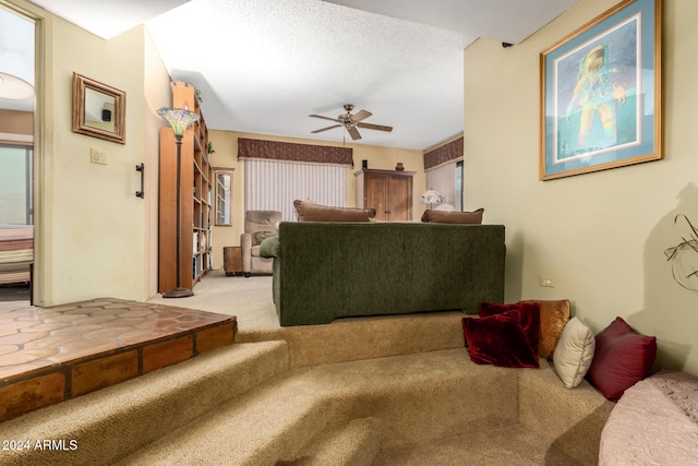 living room featuring ceiling fan, light colored carpet, and a textured ceiling