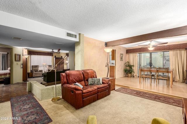 living room featuring light colored carpet, ceiling fan, a textured ceiling, and beam ceiling