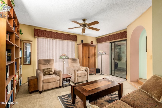 carpeted living room with a textured ceiling and ceiling fan