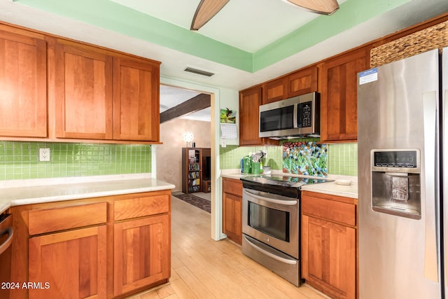 kitchen with light wood-type flooring, backsplash, and stainless steel appliances