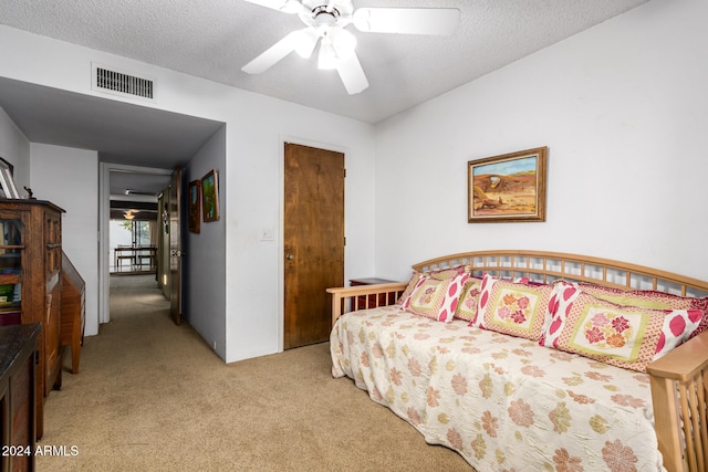 bedroom featuring a textured ceiling, light carpet, and ceiling fan