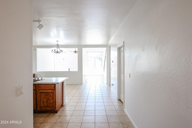 hallway featuring a textured ceiling, light tile patterned flooring, and a chandelier