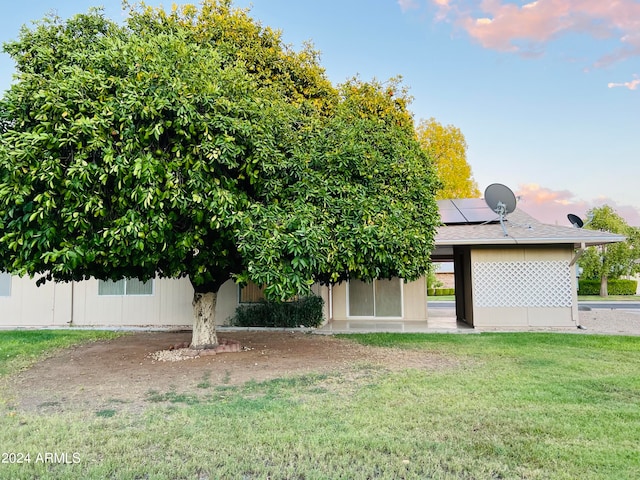 view of property hidden behind natural elements featuring solar panels and a front yard