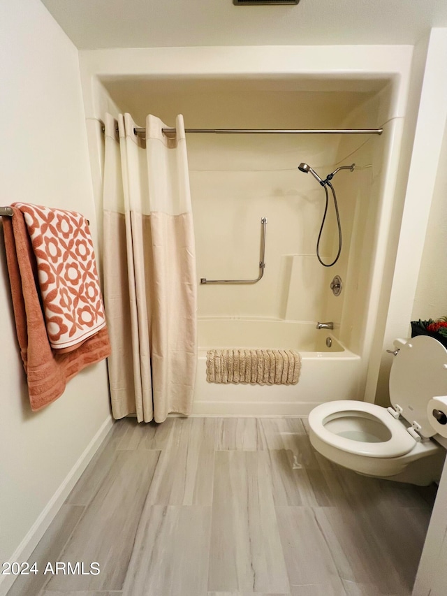 bathroom featuring shower / tub combo and toilet