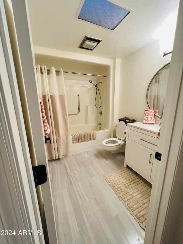 full bathroom featuring shower / bath combo, a textured ceiling, hardwood / wood-style flooring, vanity, and toilet