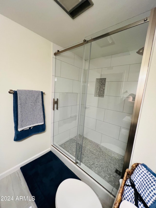 bathroom with hardwood / wood-style floors, toilet, and an enclosed shower