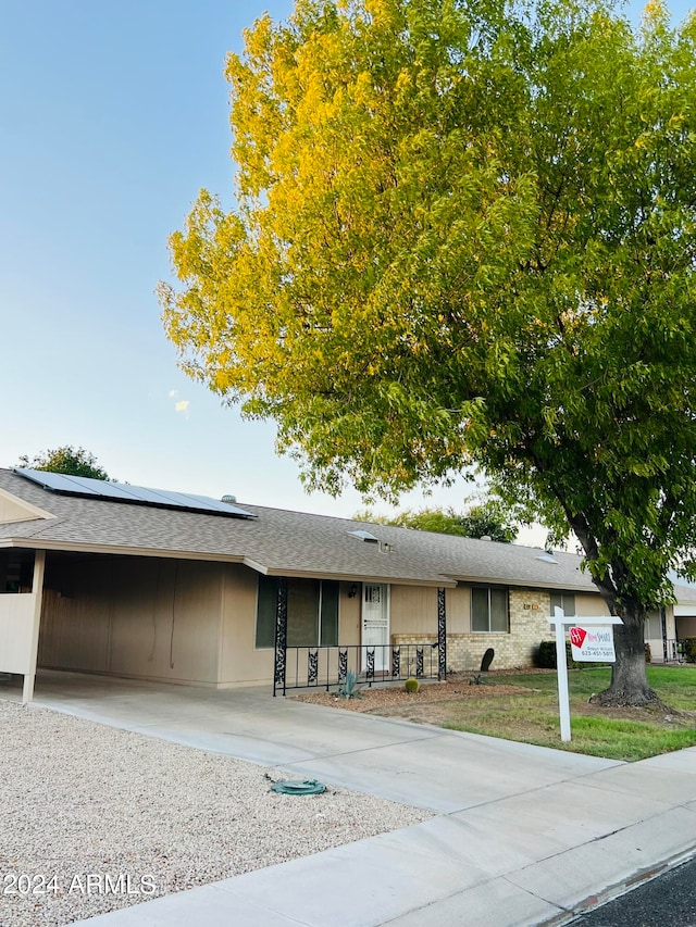 ranch-style home featuring solar panels and covered porch